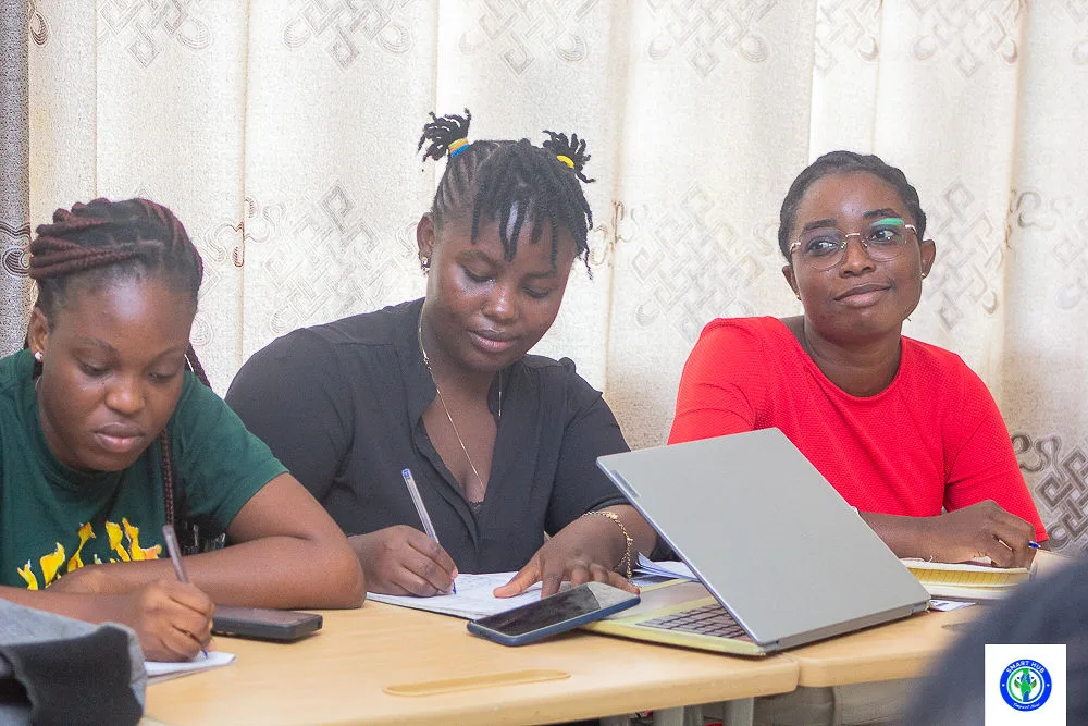Three young women working with notes and a laptop at a table.
